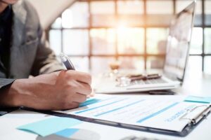A couple reviews vacation home insurance documents beside keys, a tablet, and a home inventory checklist.